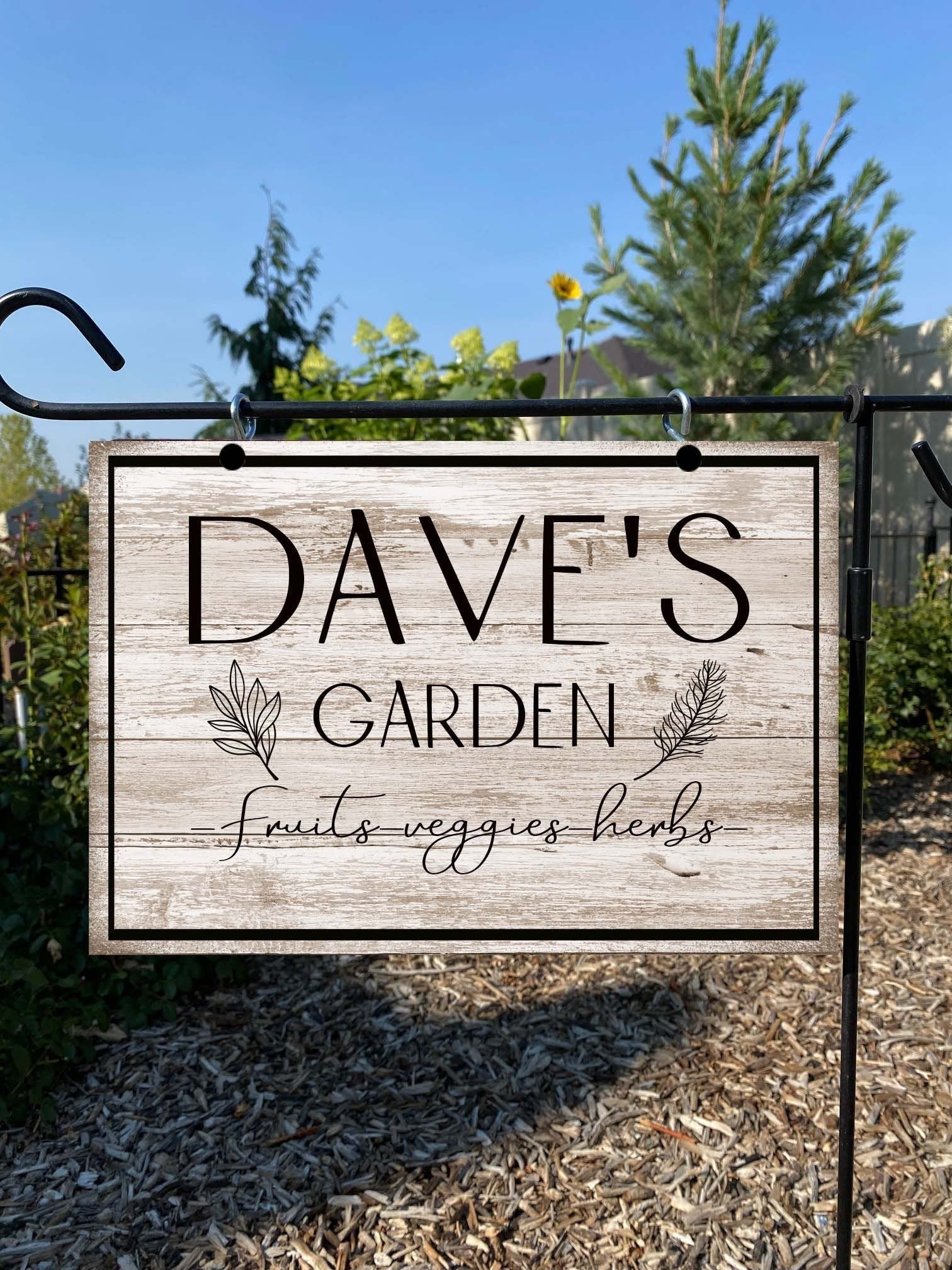 Garden sign with 'Dave's Garden' text in a natural setting